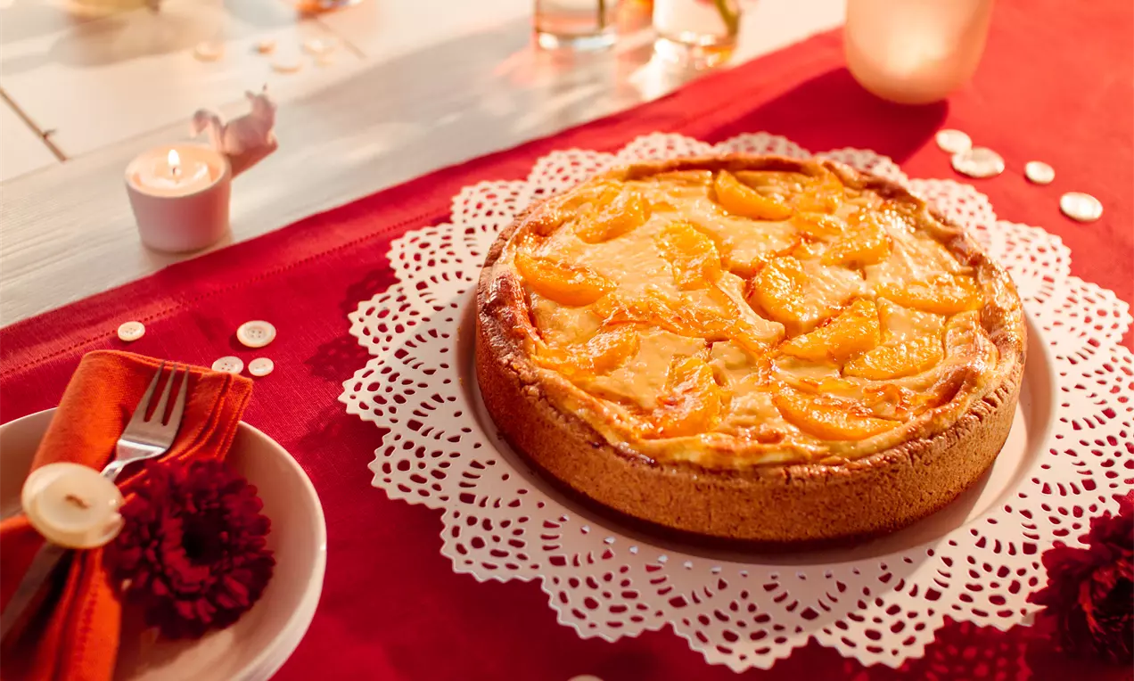 Fruchtiger Orangen-Käsekuchen mit Orangenglasur, cremiger hellgelber Füllung, goldbraunem Boden und Orangenfilets auf weißem Teller