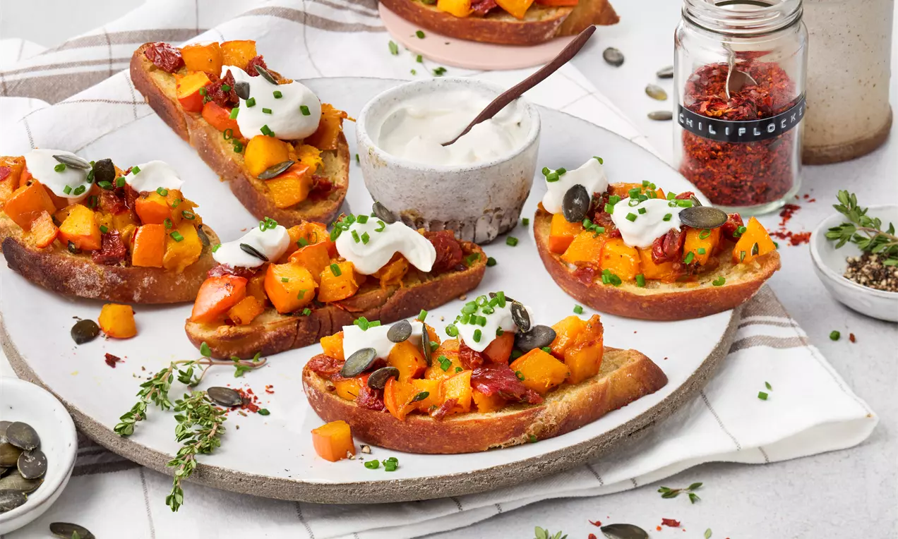 Herbstliche Kürbis-Bruschetta: knusprig geröstete Brotscheiben, belegt mit gebratenem Kürbis, frischen Tomaten und aromatischen Kräutern – ein einfaches, saisonales Rezept für Genießer.