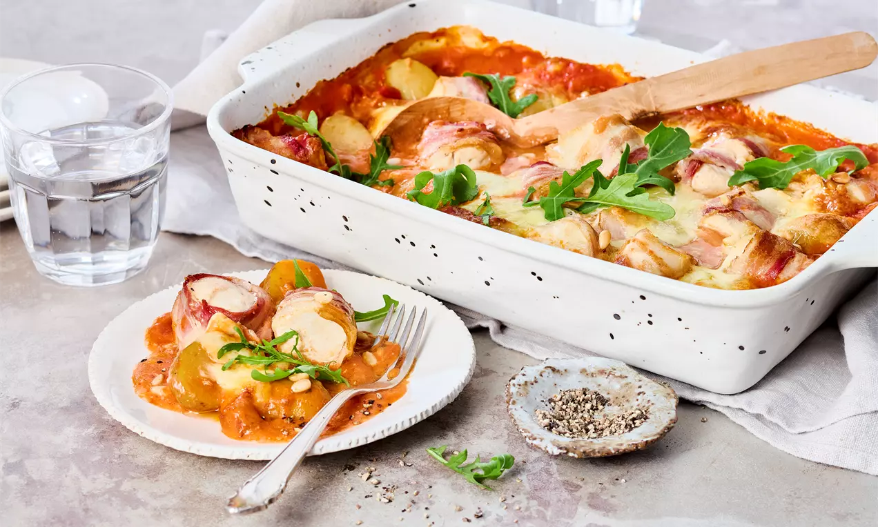 Auflaufform und Teller mit Hähnchen-Schlemmerhappen mit Bacon, Mozzarella und Kräuter-Crème – saftiges Hähnchen aus dem Ofen. Einfaches Rezept für herzhaften Genuss zum Mittag- oder Abendessen.