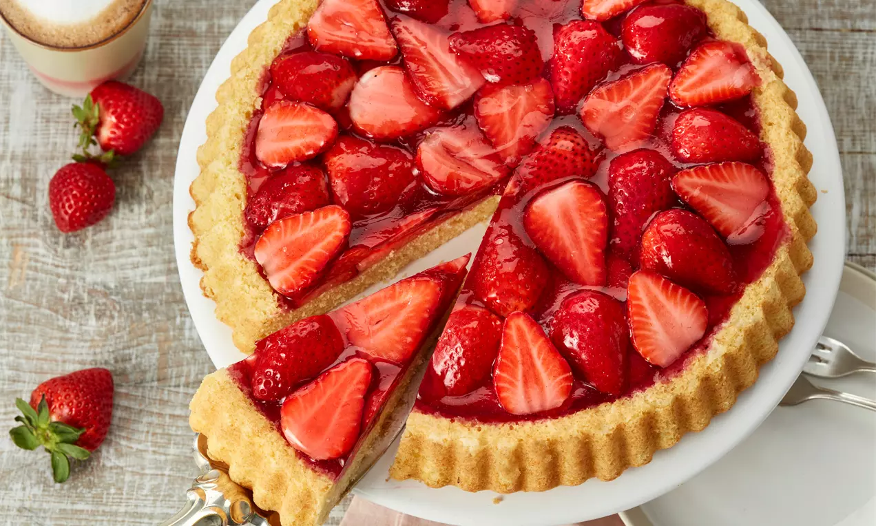 Obstboden mit saftigem goldbraunem Rührteig, dicht belegt mit glänzenden roten Erdbeeren, blauen Heidelbeeren und Aprikosen