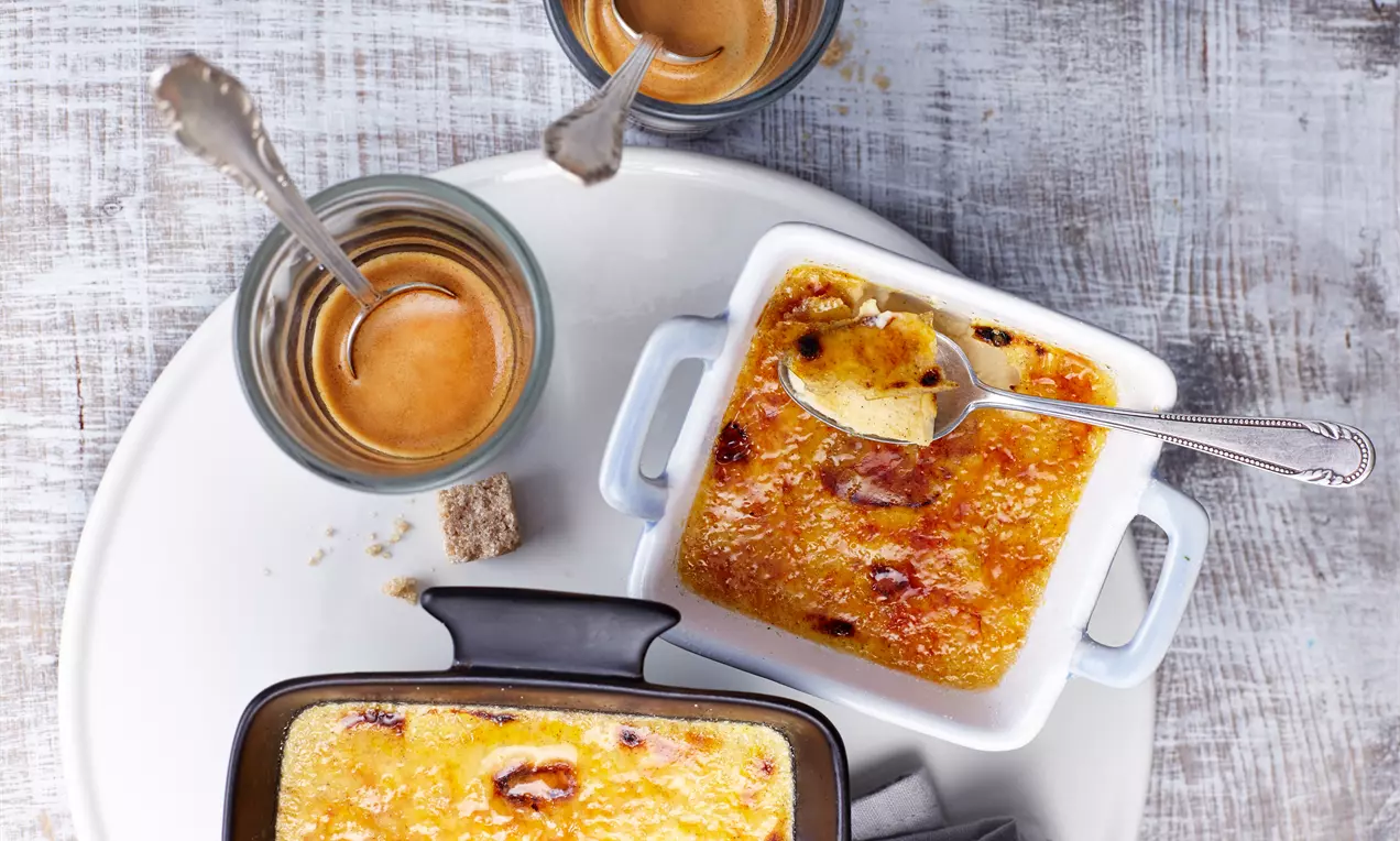 Crèma catalana mit goldener Karamellkruste in rechteckigen Förmchen, dazu kleine Tassen Espresso und ein Stück brauner Zucker auf hellem Tablett