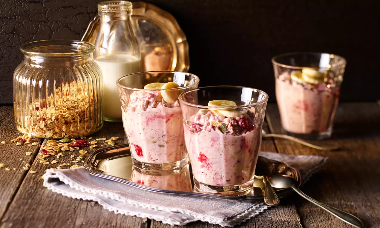 Overnight-Müsli mit cremigen Haferflocken und Joghurt, garniert mit roten Himbeeren, gelben Bananenscheiben und Chiasamen im Glas