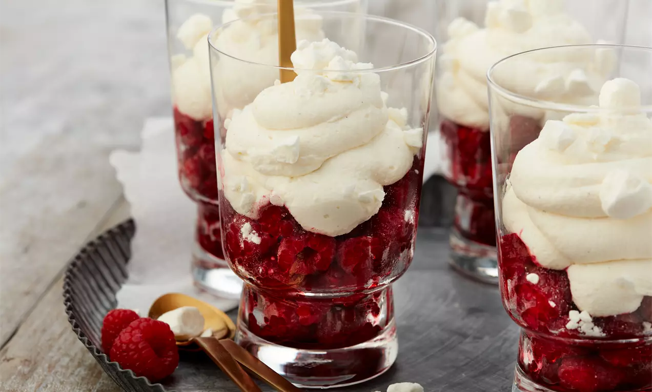 Rote Inge Dessert mit leuchtend roten Himbeeren, cremiger weißer Sahne und knusprigen Baiser-Stückchen in Dessertgläsern
