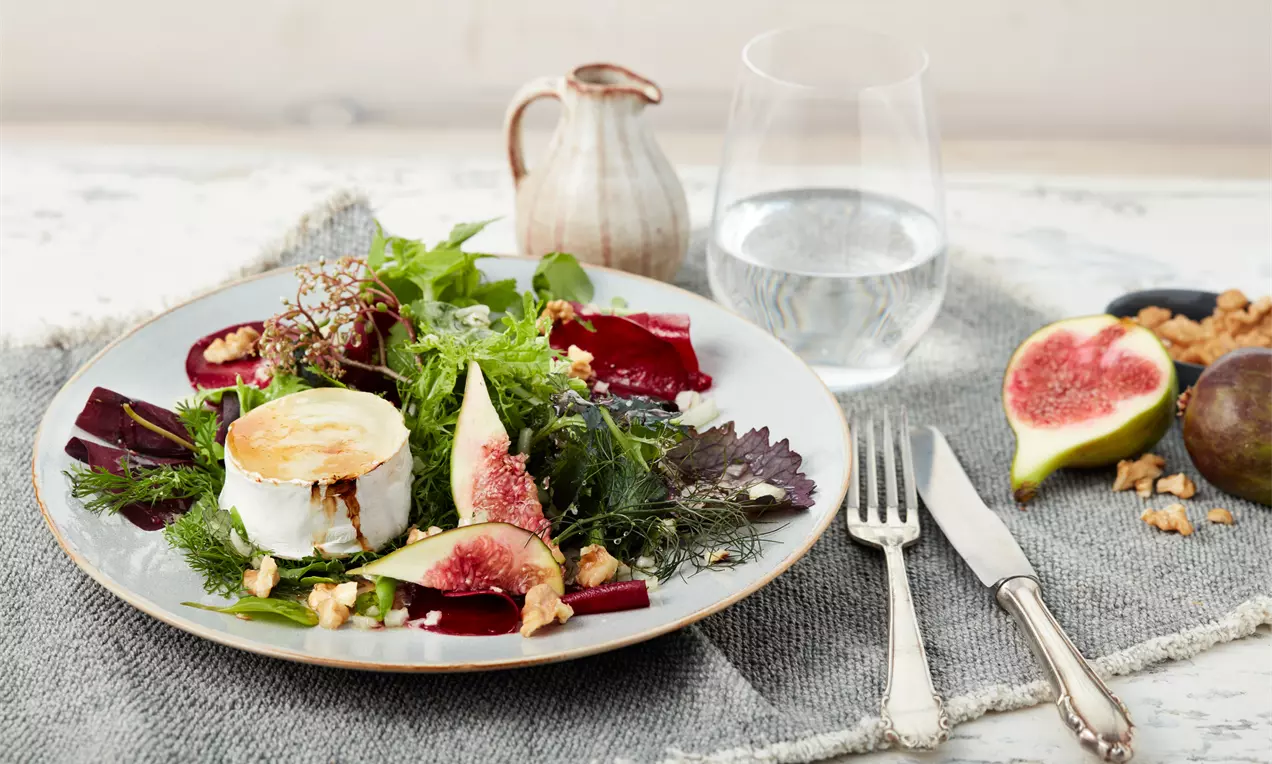 Gratinierter Honig-Ziegenkäse auf Salatbett mit grünen Blattsalaten, Feigenvierteln, Walnüssen und goldener Honigglasur