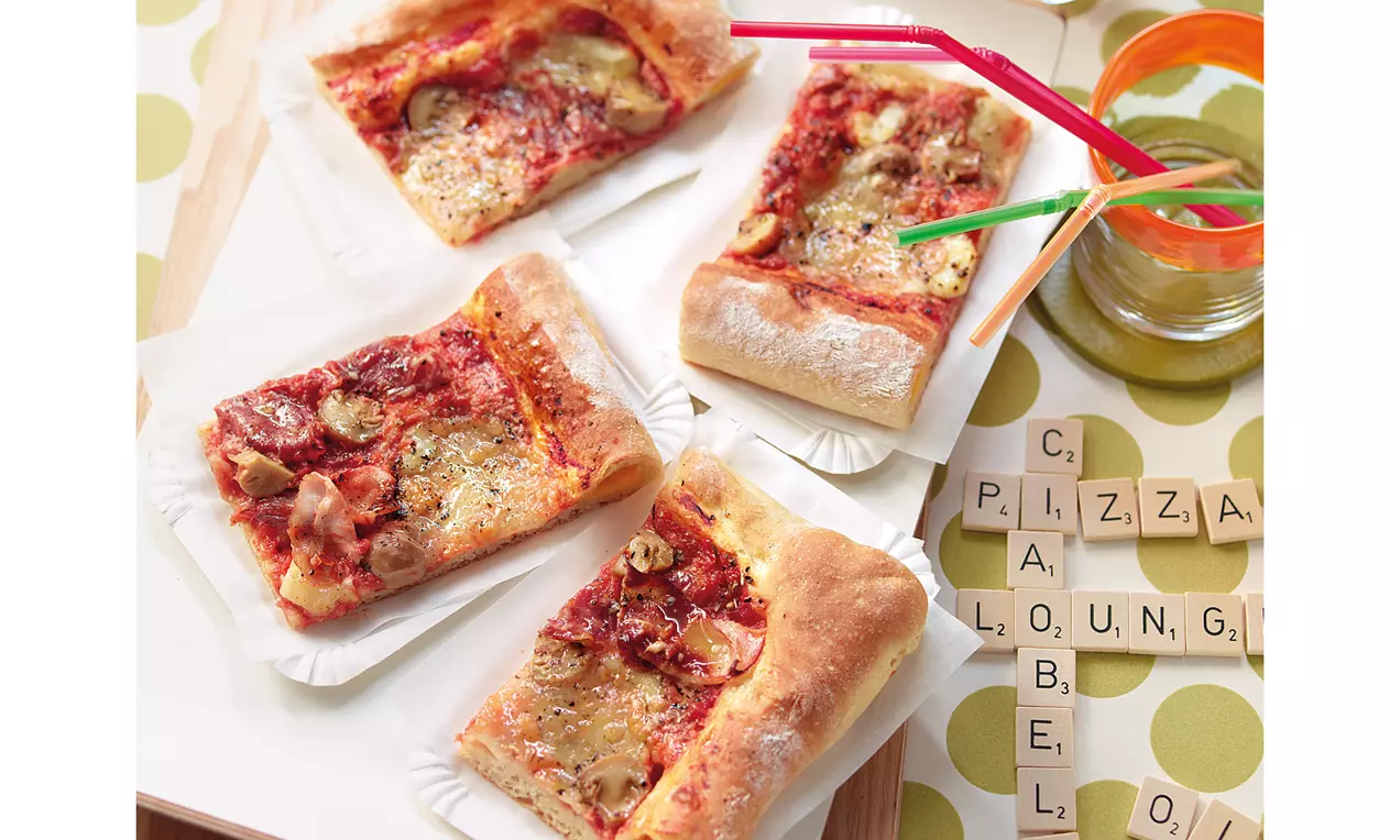 Vier rechteckige Pizzastücke mit goldbraunem Käserand, roter Tomatensauce und gebräuntem Käse auf weißen Papptellern angerichtet