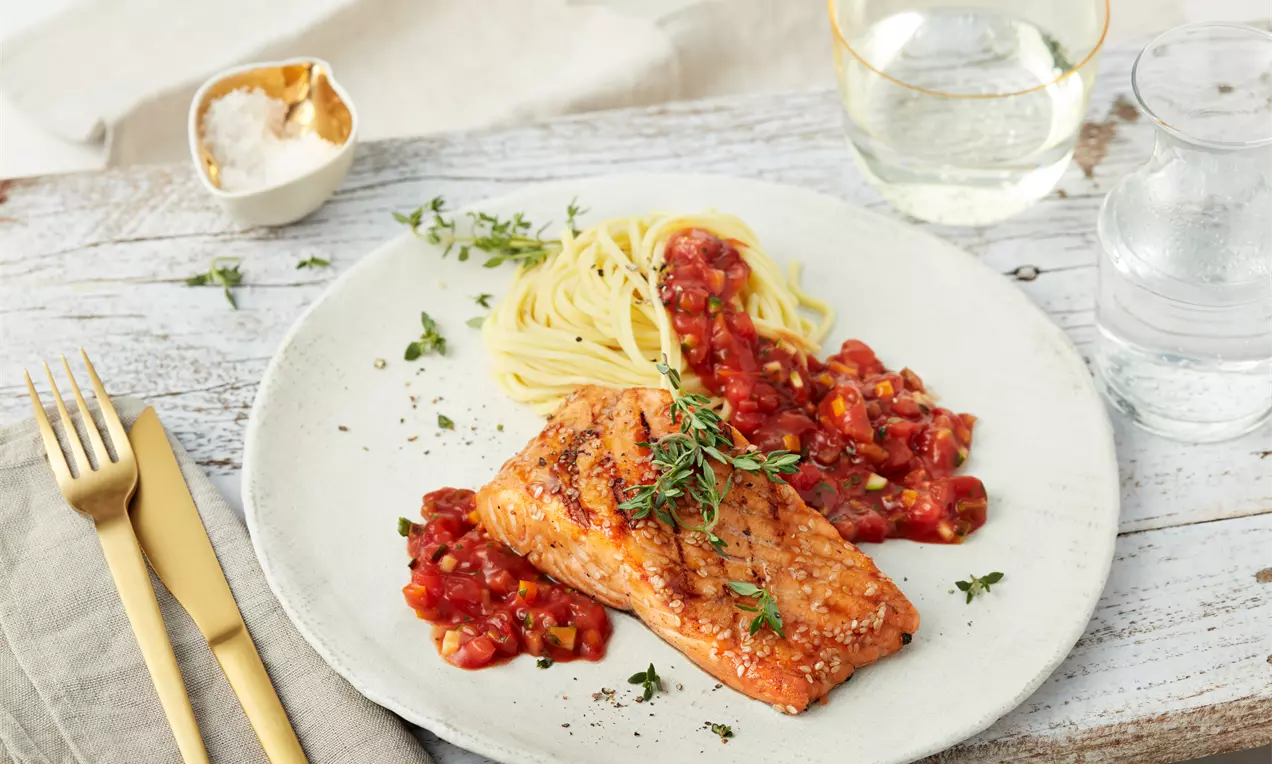 Teriyaki-glasierter Lachs mit würziger Gemüse-Bolognese und hellen Spaghetti, angerichtet auf einer Keramikplatte mit frischen Kräutern