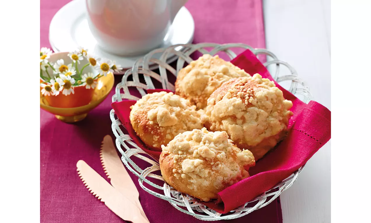 Streuselbrötchen mit goldbrauner Kruste und knusprigem, hellem Zimtstreusel, auf einem weißen Teller mit Leinenserviette