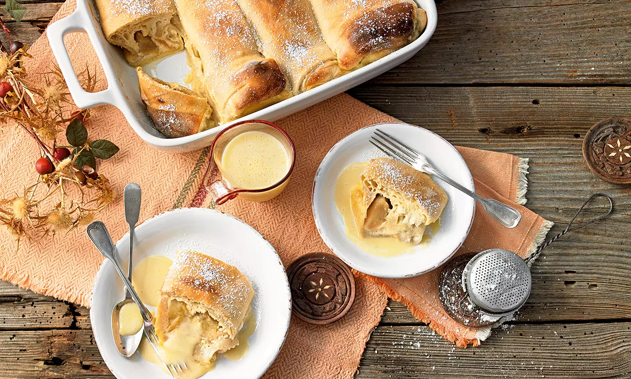 Milchrahmstrudel mit goldbraunem Teig, saftiger Quark- und karamellisierter Apfelfüllung, glänzendem weißen Sahneguss und Puderzucker