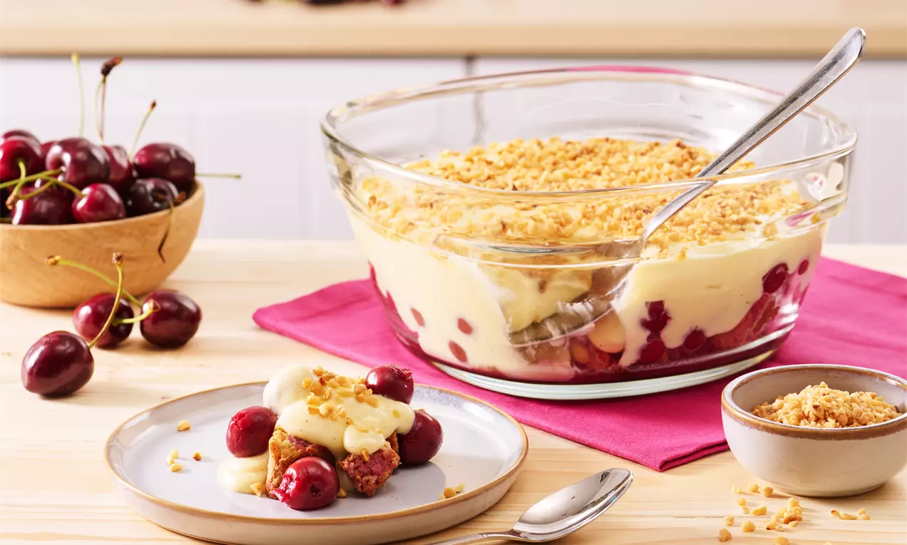 Cremiges Dessert mit Vanillepudding, saftigen Kirschen und knusprigen Bröseln in einer Glasschale, dekoriert mit frischen Kirschen