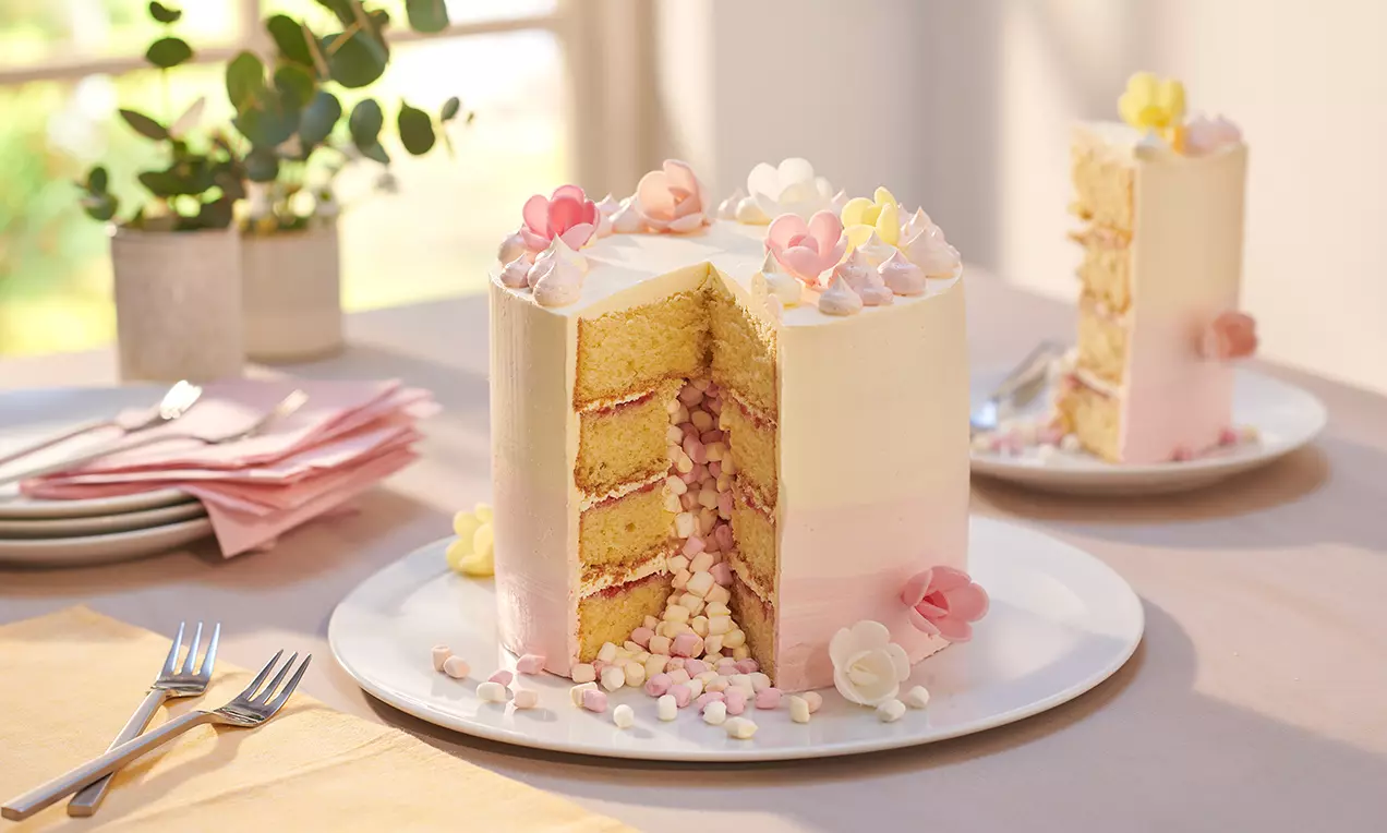 Amerikanische Buttercreme in einer glatten Schüssel mit cremiger, hellgelber Textur, Spritzbeutel und Pastellstreuseln angerichtet